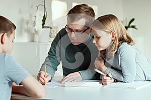 Young father at home office teaching his children during quarantine lockdown at home