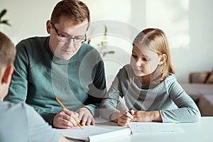 Young father at home office teaching his children during quarantine lockdown at home