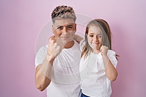 Young father hugging daughter over pink background annoyed and frustrated shouting with anger, yelling crazy with anger and hand