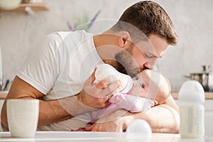 Young father kiss his baby during drinking milk