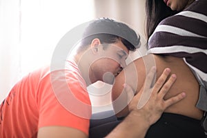 Young father kissing the pregnant wife`s belly