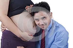 Young father listening pregnant belly