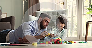 Young father and little son build together with colored blocks