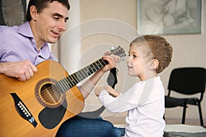 Young father and little son playing guitar