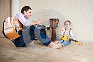 Young father and little son playing guitar