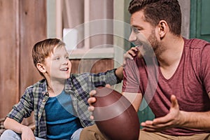 Young father with little son sitting on porch at backyard