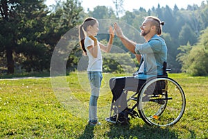 Young father with mobility impairment high-fiving daughter