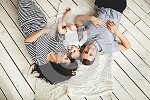 Young father, mother and cute baby lying on floor