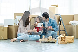 Young father and mother playing ukulele and wooden block toys with little cute daughter at home, having fun together. Happy family