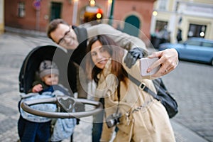 Young father and mother with son in baby stroller outdoors