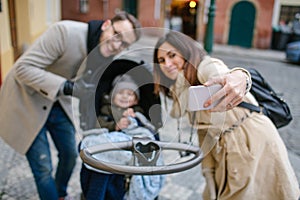 Young father and mother with son in baby stroller outdoors