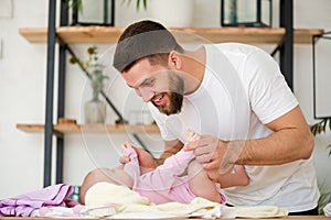 Young man play with his laying baby girl.