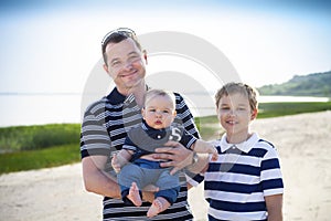 Young father playing with baby sons as at the beach