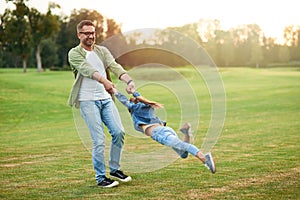 Young father playing and having fun with his little daughter in the beautiful green park on a summer day