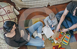 Father playing with toddler while the mother is looking at them