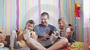 A young father plays with his daughters in dolls in the children`s room
