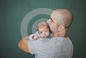 Young father with short hair kisses his newborn daughter