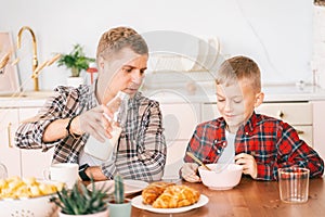 Young father and son have breakfast together, father`s day concept