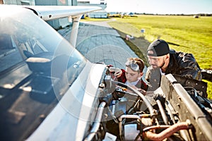 Young father and son trying to fix electrical wire system of light aircraft