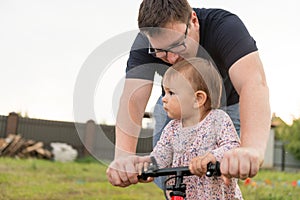 Young father spend time with Cute little one years old toddler girl child and balance bike, father`s day