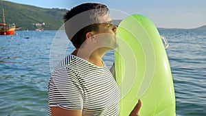 Young father surprises his kids with an inflatable swimming ring on a beach at sunset. Tourism, happiness of summertime