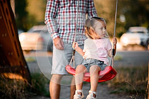 Young father swing his little daughter on swing