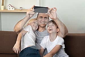 Young father takes selfie with his sons. Father and children take photo and smile. Happy family