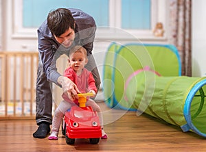 Young father is teaching his child to drive toy car. Daddy is playing with daughter