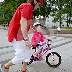 Young father teaching his daughter to ride a bike