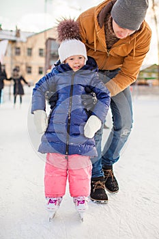Young father teaching his little daughter to skate