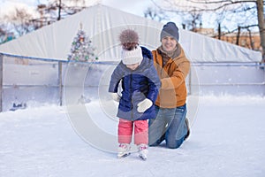 Young father teaching his little daughter to skate