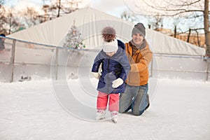 Young father teaching his little daughter to skate