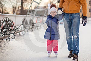 Young father teaching his little daughter to skate