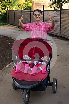 Young father with twin pram walking in the park
