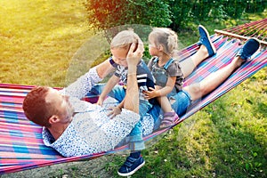 Young father with two kids having fun in hammock. Father`s day, family day, children`s day concept