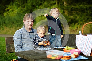 Young father and two little boys picnicking in the park