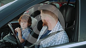 Young father using seat belt and looking at his son in the car. Slow motion