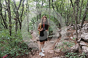 A young fearless female photographer tourist climbs the mountains along the path. Active recreation.