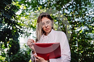 Young female agricultural engineer working in greenhouse.