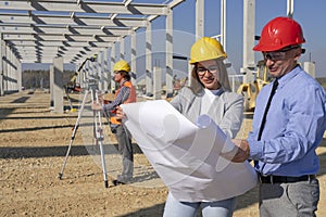 Young Female Architect and Construction Engineer Checking the Blueprint on Construction Site