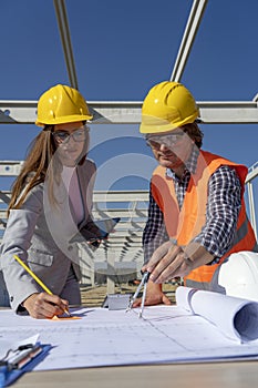 Young Female Architect and Engineer Checking the Construction Blueprint on Constraction Site