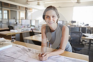 Young female architect leaning on desk smiling to camera