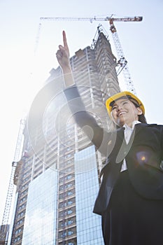 Young female architect pointing at a construction site