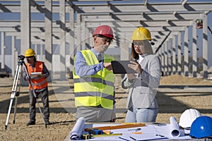 Young Female Architect With Tablet and Mature Businessman Meeting on Construction Site