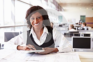 Young female architect working at desk, looking to camera