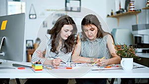 Young female architects discussing with blueprint in office