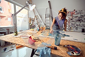 A young female artist is enjoying the process of creating a painting in the studio. Art, painting, studio