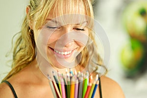 Young female artist holding colored pencils and smiling