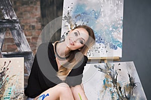 Young female artist painting abstract picture in studio, beautiful woman portrait