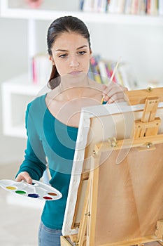 Young female artist painting picture in studio